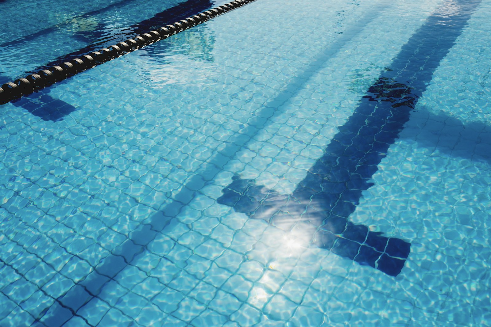 Sunlight rippling across a quiet swimming pool lane
